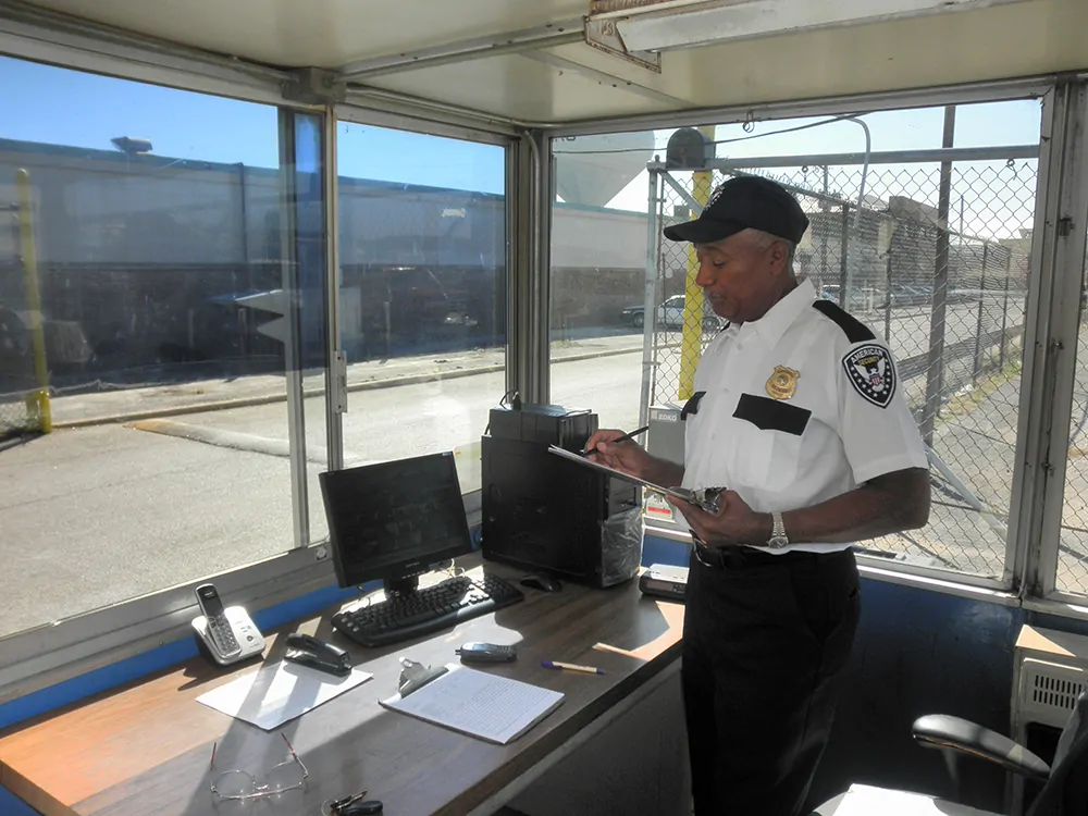 American security guard guarding in his office writing on checklist