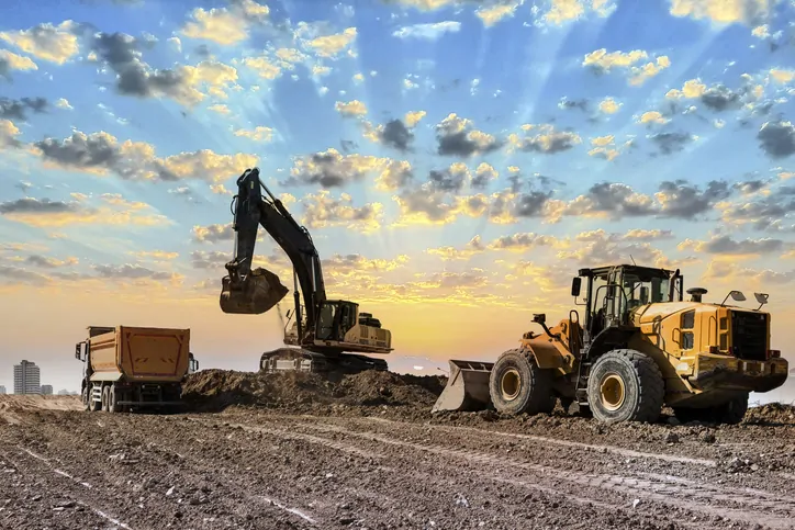 Excavators working on construction site at sunset