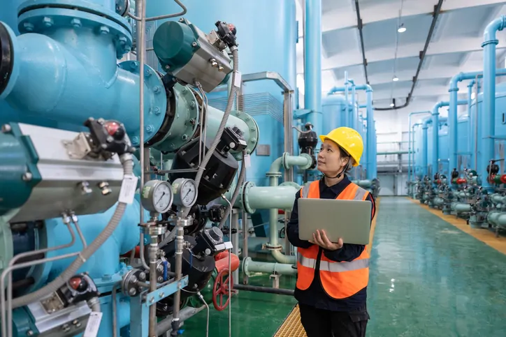 A female engineer works in a chemical plant using a laptop computer